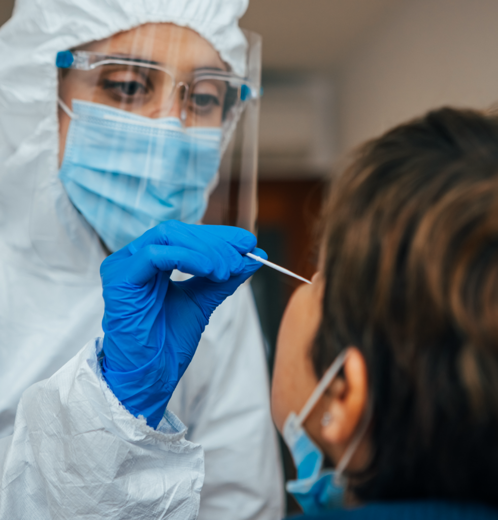 nurse in protective gear gives patient a nasal swab